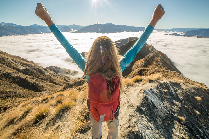 young woman standing with arms up in celebration