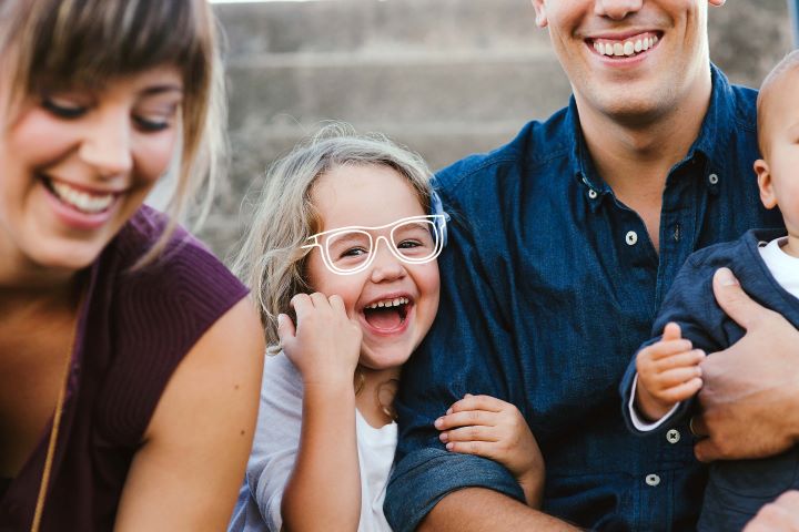 family with a little girl smiling. She has glasses drawn on her face
